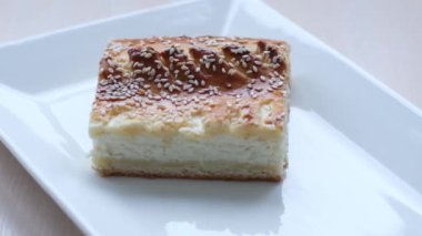 large piece On square white plate of cottage cheese dessert pastry yeast dough is decorated with sesame seeds and leaves dough like a loaf is baked village restaurant serving delicious Healthy food