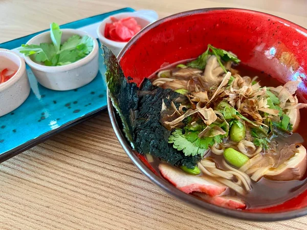 Spicy Sichuan Dandan noodles ramen with spicy dumplings combo in the traditional Japanese ramen restaurant, with Japanese fonts sake barrel translation: Invincible Great Gate. High quality photo