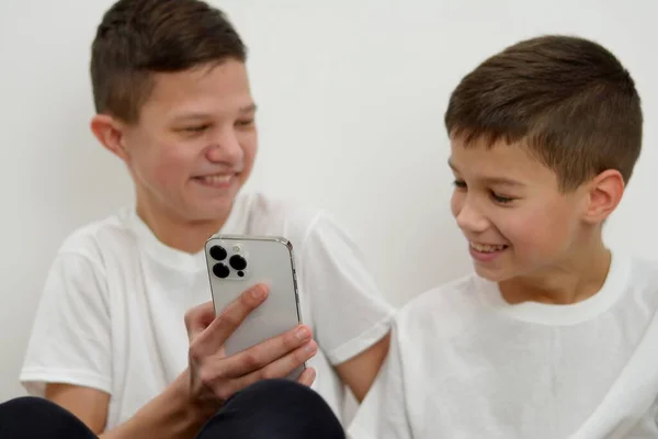 Two attractive teenagers sitting look to phone Smiling laughing surprising poking to gadget on evening brothers are talking showing photos of friends laughing classmates Ukraine Vinnitsa 2023