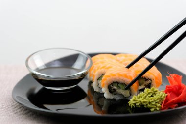  Philadelphia usulü suşi, somon balığı, füme yılan balığı avokado, siyah arka planda krem peynir. Suşi menüsü. Japon yemeği siyah tabak soya sosu beyaz arka plan