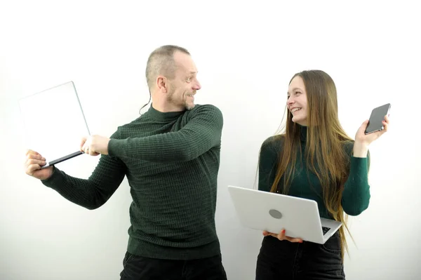 man and woman are fighting using laptop tablet and phone technology laugh play jokes on white background husband and wife teacher and student father and daughter Sensei waving book green sweater