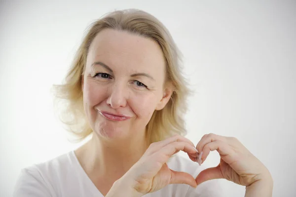 make hands heart middle-aged woman confesses love on valentines day holding lips smiling tilting head showing a heart with hands saying like this lips stretched out into tube on white background