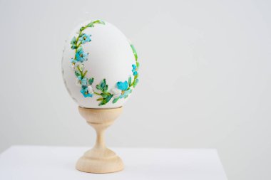 Easter holiday on stand is white egg with blue embroidery cornflowers delicate flowers embroidery with ribbons handmade on white background congratulations postcard invitation place for text unreal
