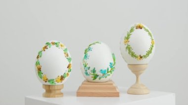 close-up of three white eggs on stands embroidery with ribbons on an eggshell example technology beautiful ornament handmade Easter holiday easter eggs decoration drawing on eggs as gift