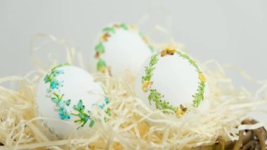 camera smoothly zooms away while shooting Three large goose ostrich turkey chicken eggs with ribbon embroidery on an eggshell in nest with sawdust handmade making embroidered eggs for Easter