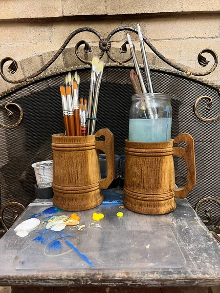 country house home furniture craft wood utensils Handmade furniture artists workshop two large wooden mugs beer pints with tassels handles lowered down natural pile for working with oil paints