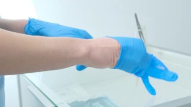 Individual protection products vinyl disposable gloves in spread of virus and protection against infections. Women is dressing her hands in gloves. The coronavirus protection trend is COVID-19.