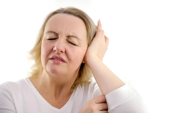 stock image headache middle-aged adult woman interferes with noise she closes her ears squinting her eyes bent over with a displeased face hurts head pain in the ear white background white jacket unpleasant