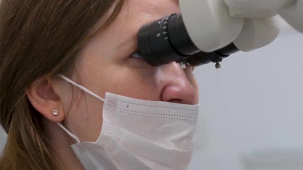 Zbliżenie Twarz Kobiety Lekarz Patrzy Mikroskop Masce Nos Oddycha Swobodnie — Wideo stockowe