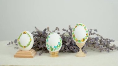 Lavanta çiçekli güzel uzun lavanta rengi pankart ve ahşap üzerine paskalya için üç yumurta. Üzerinde yumurta desenleri, yumurta kabuğu süslemesi üzerine farklı renk ipliklerle işlenmiş.