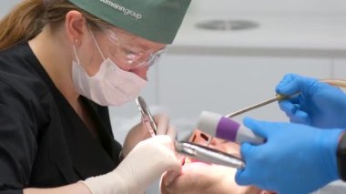 hard tooth extraction, tooth extraction tools Gracie curette, piezo scaler, piezo scaler attachment, piezo scaler wrench, luxator woman doctor dentist removes a man patient Ukraine Vinnitsa 2023