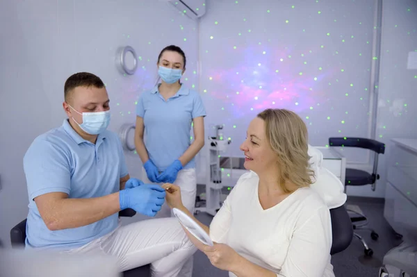 dental clinic patient reception in hall with stars intimate atmosphere doctor and nurse in masks wearing blue gloves offer women color options teeth whitening latest technology