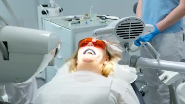 liquid cofferdam to isolate gums from action of bleaching agent optragat rotary spreader classical dental coloring for determining color of teeth woman in a dental chair is trying to communicate