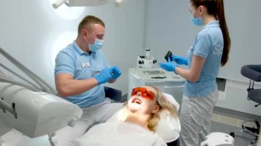 optragate mouth expanderdental clinic doctor and assistant nurse assistant tearing package of sterile instruments while preparing for dental procedures dental treatment whitening filling cleaning