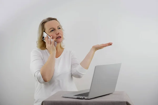woman talking on phone and pointing with hand at laptop table clarification of relationships problem solving dissatisfied customer home order delivery communication with superiors subordinate children