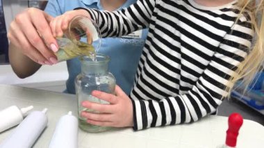 Scientific experiment at home. Laboratory tests for school homework. Parent mother with daughter kid making chemical test at home kitchen. Nanny babysitter teacher help in protective glasses
