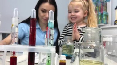 Little scientist. Curious daughter play with mom engaged at education activity make funny experiment. Interested small girl watch elder sister doing chemical test use chemistry set kids
