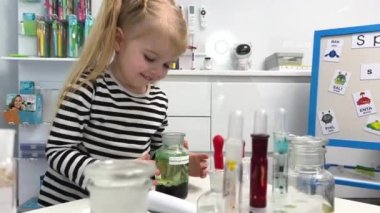 Children girl schoolgirl, Hand holding flask while doing chemistry experiments, in science class, girl used magnifying glass, peering into mouth glass bottle, where light smoke was coming out