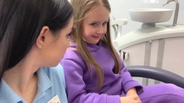 Beautiful cute little girl is afraid of the dentist The dentist is talking to her, calming her down, she is afraid to lower her eyes Childrens dentistry communication with children