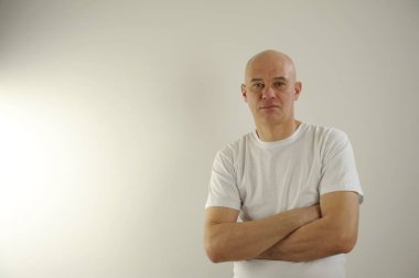 Cheerful guy smiles happily. Confident bald man dresssed casually with arms folded. Isolated over gray studio background. High quality photo