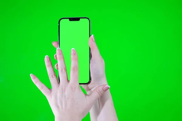Beautiful girl holding a smartphone in the hands of a green screen green screen hand woman holding mobile smart phone with chroma key green screen on white background, new technology concept