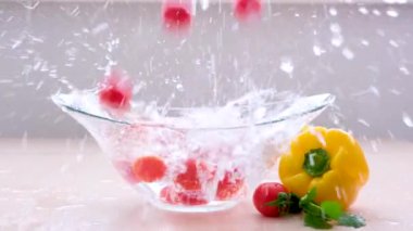 slow motion video cherry tomatoes fall into clear water a lot of splashes around on the table vegetables wash food germ protection health vitamins proper nutrition Falling red cherry tomato into water