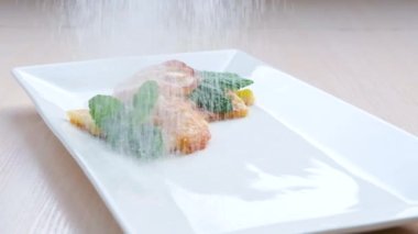 pancakes sprinkled with powdered sugar Confectioner sprinkles powdered sugar on delicious Dutch baby pancake. High quality FullHD footage