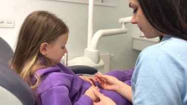 the girl in dental chair is afraid to open her mouth the doctor to interest her in toys the ring gives look at each other Calmness and relaxation approach to children pediatric dentistry young