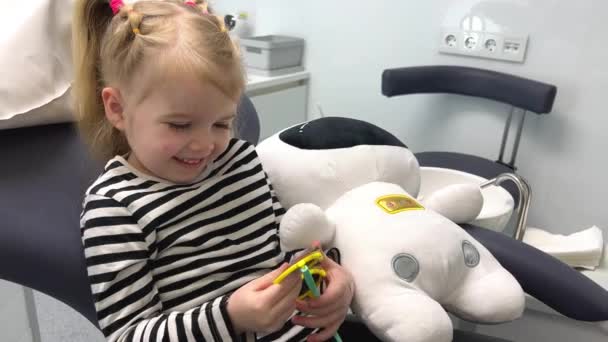 Маленькая Девочка Полосатой Блузке Осматривает Солнцезащитные Очки Стоматологическом Кресле Защищая — стоковое видео