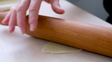 rolling out the dough with a rolling pin female hands in process of swinging a piece of dough for pies pierogi dumplings dumplings delicious homemade food cooking adult person real people wooden table