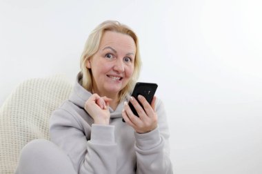  woman has idea to buy gift for herself She playfully looks into frame raising eyebrows opening eyes biting lip and slyly cheerfully holding phone in hands call order dream realization of desire