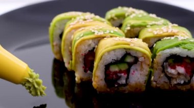 Menü yeşili Japon dürümleri avokado, omlet, susam ve salatalık tabakta yakın plan. Yatay bir şekilde, siyah bir restoranda nefis Japon yemekleri servis ederken.