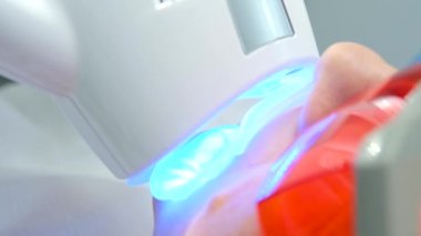 close-up of a womans face under apparatus Beyond Poluse Plus Advanced Whitening System with Dental UV Laser Whitening Device in glasses protective against ultraviolet whitening teeth