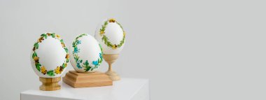 lavender background postcard baner calendar empty space holiday easter eggs embroidery ribbons on eggshell krashanka three eggs on special wooden stands on a white background