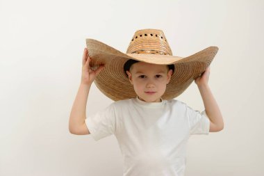 child 4 - 5 years old boy in huge hat big hat on his head white background white t-shirt knight cowboy Mexican smile childrens clothing confidence social insurance buying a new apartment