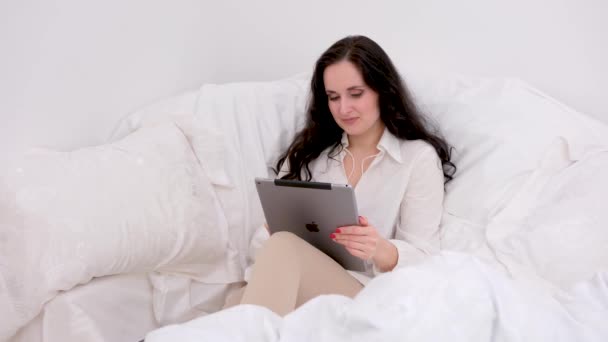 Beautiful Black Haired Woman Sits White Sofa Duvet Hands Tablet — Stockvideo
