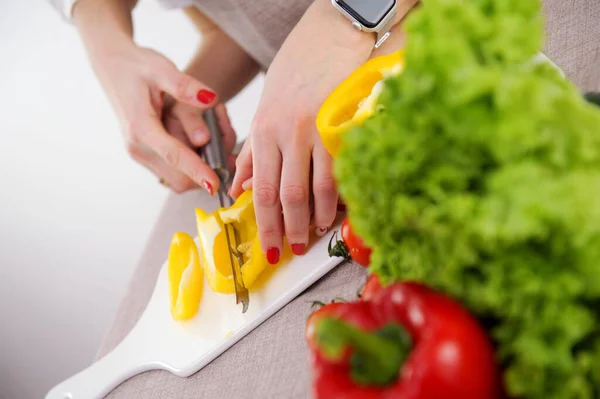 adult teaches child to cut vegetables mother helps son to cut yellow bell pepper close-up hands knife porcelain whiteboard healthy vegetables first steps in cooking training
