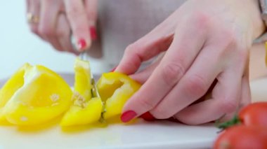 adult teaches child to cut vegetables mother helps son to cut yellow bell pepper close-up hands knife porcelain whiteboard healthy vegetables first steps in cooking training