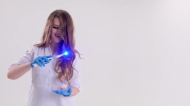 Photopolymer lamp Doctor Fairy with a glowing blue lamp in a white medical suit Dentist treatment of teeth prosthetics put fillings treat gums caries beautiful woman on white background studio ad