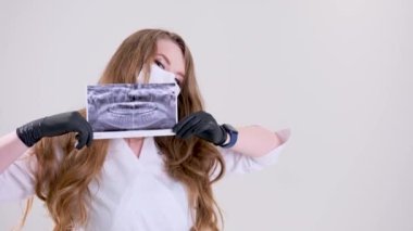 beautiful female dentist in mask holds panoramic shot of oral cavity in hands black gloves confidence doctor nurse assistant dental treatment prosthetics removal of teeth roots filling canals x-ray