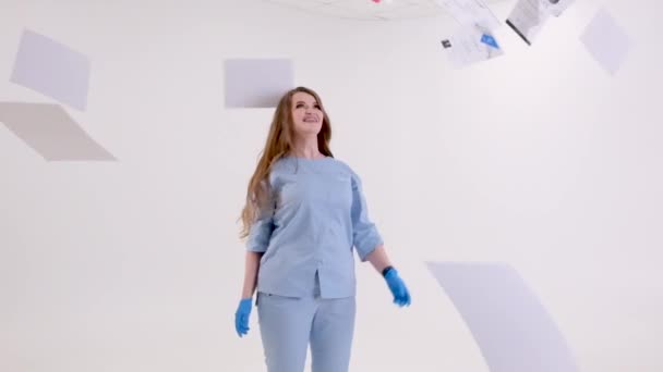 青い医療スーツと衛生手袋を着た女性医師が研修中の医科大学卒業証明書の中心に立っています歯科大学教育過去数年間 — ストック動画
