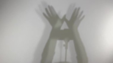 strange video on white background shadows of hands make an eagle wave around the camera on a stand on a selfie stick hands show the shadow class Shadow game