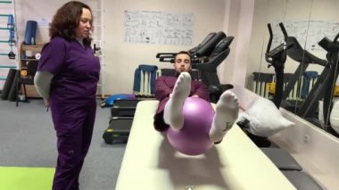 two doctors in frame physical education one doctor man shows exercises with a ball purple uniform treadmills sports activities for the rehabilitation of people after accidents injuries Ukraine 2023