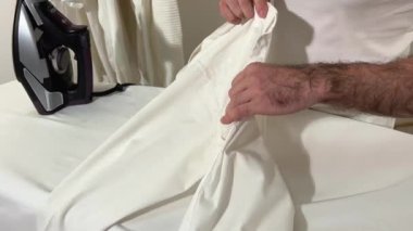 Erkek kıllı gömleği okşuyor. Kolunu ütü masasının arka planına çeviriyor. Demir gibi bir insan.