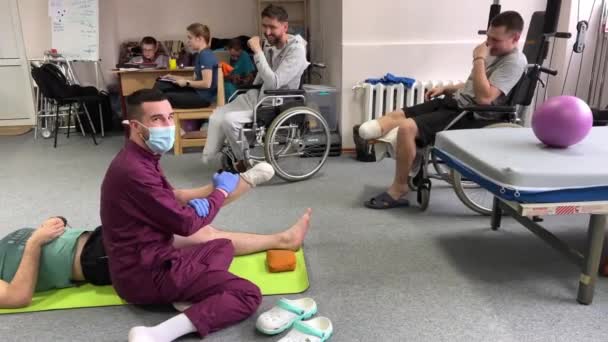 Doctor Lilac Suit Mask Tells People Wheelchairs How Gymnastics Rehabilitate — Stock Video