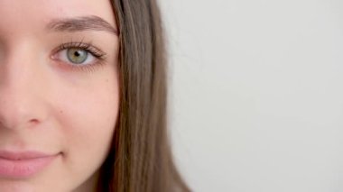 Portrait of young smiling woman looking happy on white background. Big smile on her face, looking beautiful and cute with hands touching her cheek. half face close-up space for text