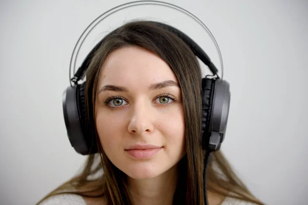 close-up face of girl in headphones on white background studio near laptop slow motion video close look beautiful young face cute woman freelance work as musician social help communication