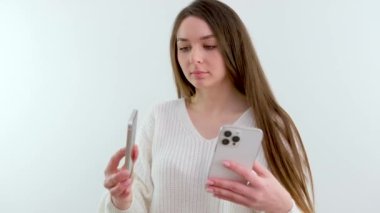 comparison of two iPhone phones iPhone 13 Pro Max and iPhone 11 dual camera 3 cameras on the gadget beautiful young girl with long hair in a white jacket in studio examines two iPhone smartphone