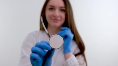 girl doctor closes lens with phonendoscope to black background beginning or end about doctors open camera Close Medical secret blue gloves white medical gown White studio advertising latest drugs