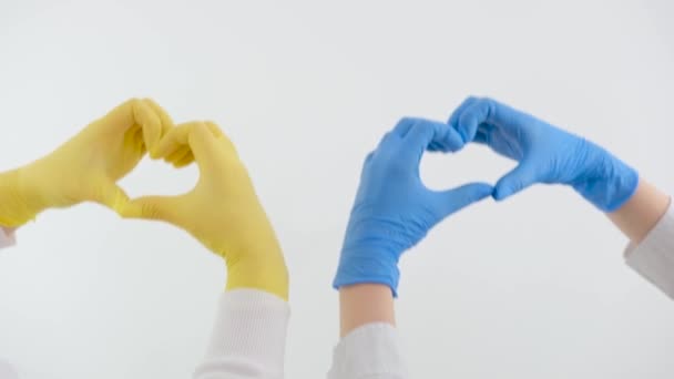 心脏病的心脏科治疗在无法辨认的工作室里帮助两位医生的手在白色背景下显示出他们的心脏 — 图库视频影像